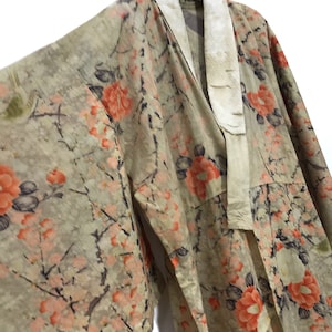 May include: A vintage kimono with a floral pattern in shades of pink, orange, and green. The kimono has a white collar and is made of a lightweight fabric.