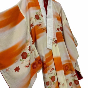 May include: A traditional Japanese kimono with a white and orange striped pattern and floral embroidery. The kimono has a white collar and a red lining.