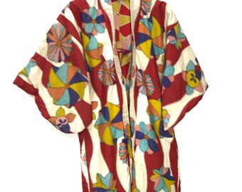 May include: A red and white kimono with a colorful floral and geometric pattern. The kimono has long sleeves and a wide collar.