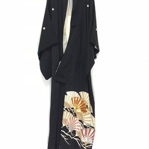 May include: A black silk kimono with a white lining and gold and red fan designs. The kimono has small white flowers embroidered on the shoulders.