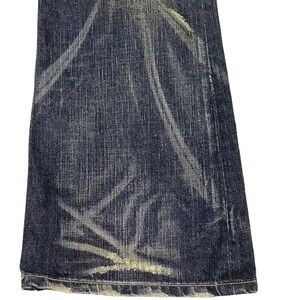 Puede incluir: Primer plano de una secci&oacute;n de vaqueros de mezclilla azul oscuro con detalles blancos descoloridos y desgastados. Los vaqueros tienen un aspecto desgastado con vetas de color claro y un dobladillo deshilachado, lo que sugiere un estilo vintage o pre-usado.