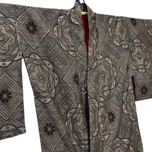May include: A gray and brown patterned kimono with a red lining. The kimono has a floral design with a geometric pattern.