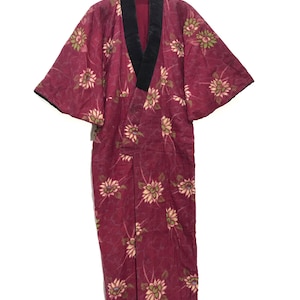 May include: A burgundy robe with a black collar and floral print. The robe has short sleeves and a long length.