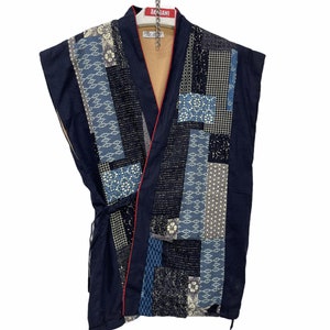 Könnte beinhalten: Ein ärmelloses Kimono in Marineblau mit rotem Saum und einem Patchwork-Muster aus verschiedenen blauen und weißen Mustern. Das Kimono hängt an einem Kleiderbügel mit einem roten Etikett, auf dem "AKASAMI" steht.