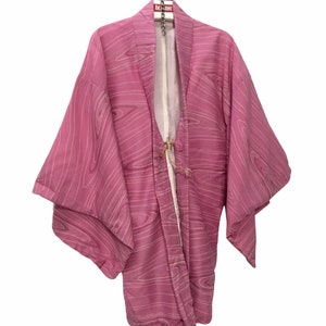 May include: A pink Japanese kimono with a white wave pattern. The kimono is hanging on a hanger with a red tag that says "AKASAMI".