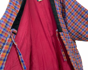 Puede incluir: Un kimono de cuadros rojos, azules y amarillos con cuello de terciopelo negro. El kimono está abierto y el forro es de color rojo sólido.