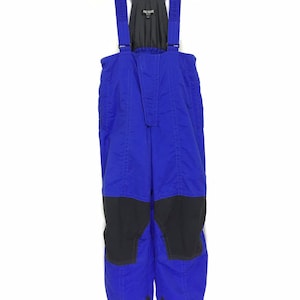 Könnte beinhalten: Blaue Ski-Overall mit schwarzen Akzenten und verstellbaren Trägern. Der Overall hat einen Reißverschluss und ein Markenetikett mit der Aufschrift "Pure Source".