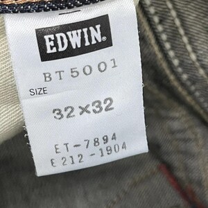 Puede incluir: Primer plano de una etiqueta blanca de vaqueros Edwin. La etiqueta muestra el nombre de la marca "EDWIN" en un rect&aacute;ngulo negro. Debajo, las palabras "BT 5001" y "SIZE". La etiqueta indica una talla de 32x32 pulgadas (81x81 cm).
