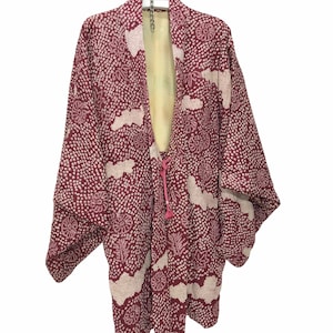 May include: A burgundy Japanese kimono with a white and beige pattern, hanging on a white hanger. The kimono features a dotted design with floral and leaf motifs. A pink drawstring is visible at the front, and the interior lining is a pale yellow.