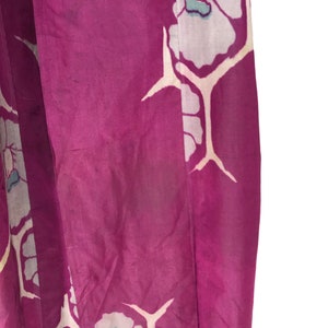 May include: A close-up of a purple fabric with a white floral pattern. The fabric has a silky texture and is likely a kimono.