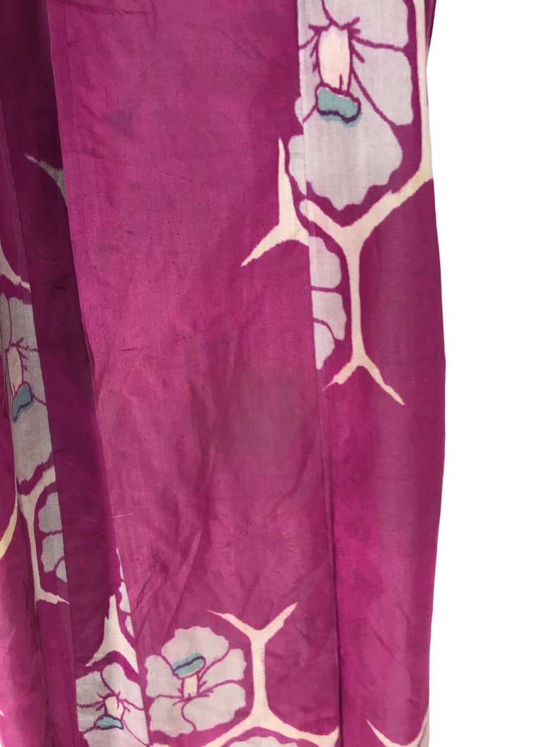 May include: A close-up of a purple fabric with a white floral pattern. The fabric has a silky texture and is likely a kimono.