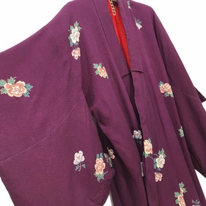 May include: A purple silk kimono with floral embroidery. The kimono has a traditional Japanese design with a wide collar and long sleeves.
