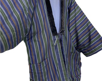 Puede incluir: Un kimono de rayas azules y verdes con cuello de terciopelo negro. El kimono tiene un lazo en la cintura y dos bolsillos.