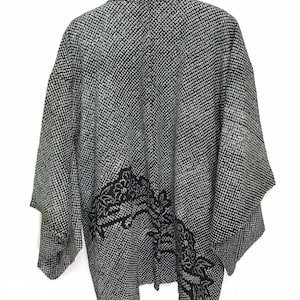 May include: A black and white patterned kimono with a black floral design on the right side.