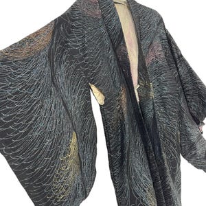 Puede incluir: Un kimono de seda negro con un patrón de remolino en dorado, azul y rosa. El kimono está colgado en una percha.