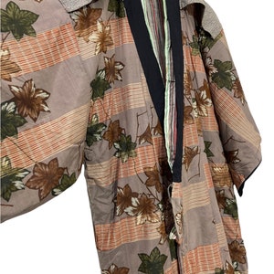 May include: A brown and beige kimono with a floral pattern of leaves and flowers. The kimono has a black collar and a green and red striped inner lining.