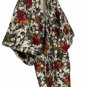 May include: A white kimono with a floral pattern featuring red, orange, green, and purple leaves. The kimono has a traditional Japanese design and is made of a lightweight fabric.