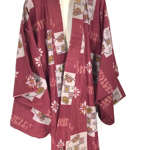 May include: A red kimono with a geometric pattern of squares and flowers in pink, white, and yellow.
