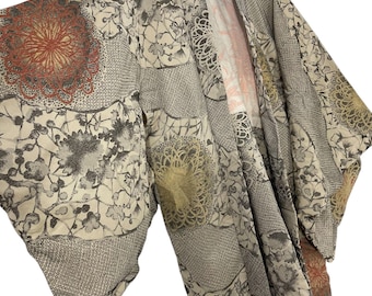 Puede incluir: Un kimono japonés tradicional con fondo beige y un patrón de diseños florales marrones, rojos y amarillos.