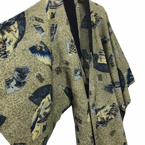 May include: A beige kimono with a navy blue collar and trim, adorned with a repeating pattern of stylized fans and landscape scenes in shades of blue, yellow, and gray. The fabric has a subtle, speckled texture.