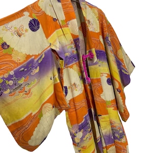 May include: A vintage Japanese kimono with a colorful floral and wave pattern in shades of orange, yellow, purple, and white. The kimono has a pink tassel tie.
