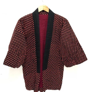 May include: A black and red quilted kimono with a geometric pattern. The kimono has a black collar and a red lining.