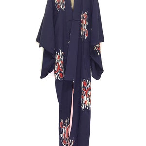 May include: A navy blue kimono with a white and red floral pattern. The kimono has a pink lining and is hanging on a hanger.