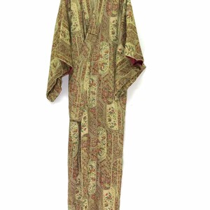 May include: A long, green and brown patterned kimono with a red lining. The kimono is hanging on a white hanger.