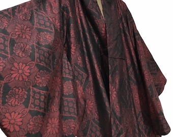 May include: A burgundy kimono with a floral pattern in black. The kimono is hanging from a chain and has wide sleeves. The fabric has a sheen, and the floral design is visible throughout the garment.