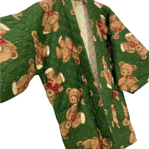 May include: A green quilted kimono with a teddy bear print. The kimono has a cream-coloured lining and a traditional Japanese style.