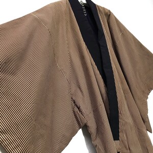 May include: A brown and black striped kimono with a black collar. The kimono is hanging on a hanger.