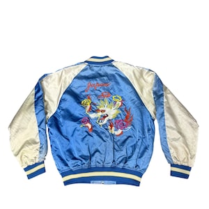 May include: Blue satin bomber jacket with cream-colored sleeves and a colorful embroidered dragon design. The back of the jacket features the word "Japan" in red script above the dragon. The jacket has blue and yellow striped trim.