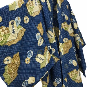 May include: A blue and gold patterned kimono with a traditional Japanese design. The kimono features a repeating pattern of coins and other symbols.