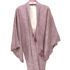 May include: A mauve-colored Japanese kimono with a textured weave and a burgundy floral design. The kimono is hanging on a white hanger with a red "AKAGAMI" label.