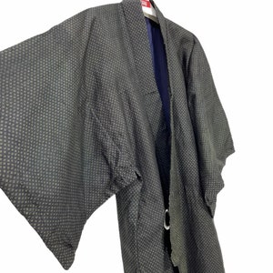 May include: A black and green patterned kimono with a navy blue lining. The kimono is tied with a black sash.