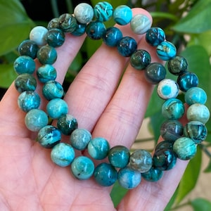 May include: A double-strand bracelet made of green and blue gemstone beads. The beads are round and have a mottled pattern.