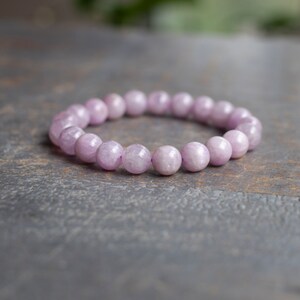May include: A bracelet made of light purple gemstone beads. The beads are round and have a smooth, polished finish.