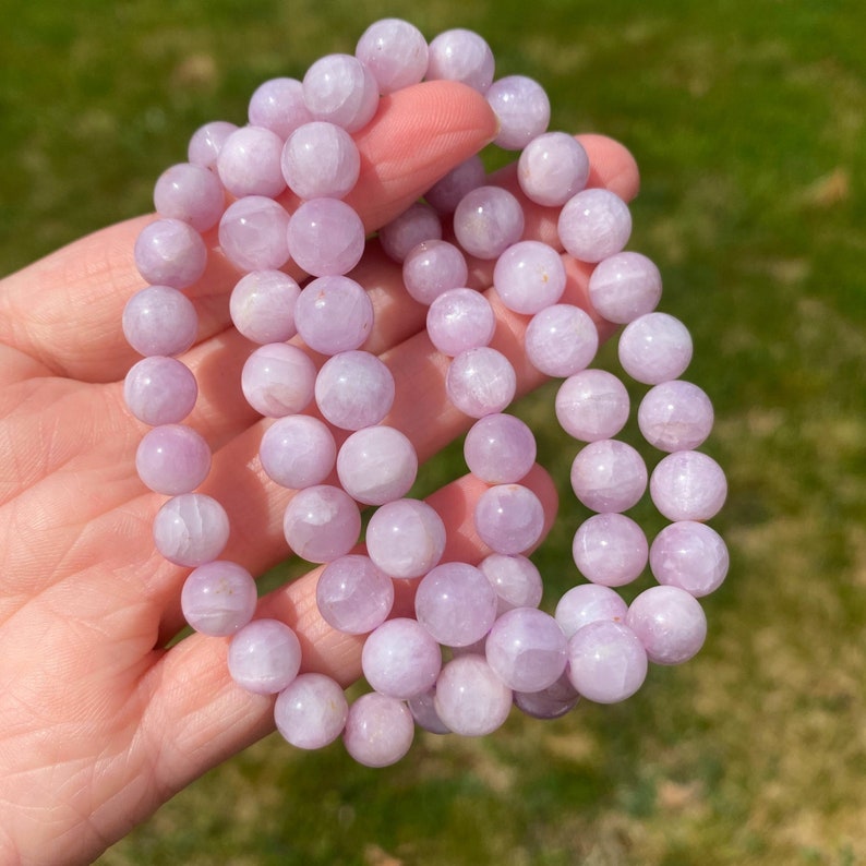 May include: A bracelet made of lavender amethyst beads. The beads are round and smooth, and they have a light purple colour. The bracelet is made of natural stone and is approximately 8 inches in length.