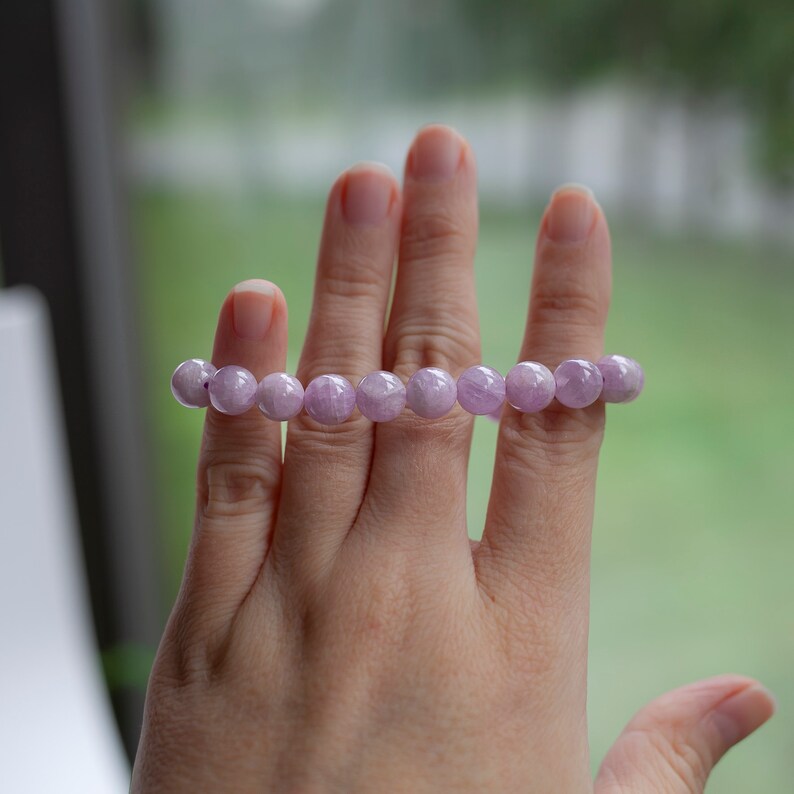 May include: A bracelet made of lavender amethyst beads. The beads are round and have a smooth, polished finish.
