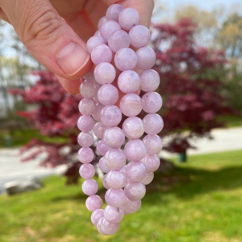 May include: A strand of light purple gemstone beads, possibly amethyst, strung together to form a bracelet. The beads are round and smooth, with a subtle shimmer.