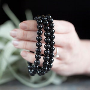 May include: A triple strand of black onyx beads, each strand is made of round, smooth beads. The beads are strung on a clear elastic cord.