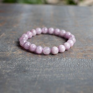 May include: A light purple gemstone bracelet with round beads.