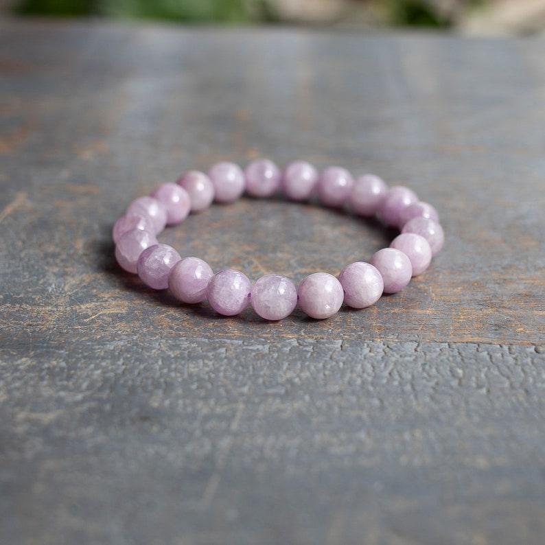 May include: A light purple gemstone bracelet with round beads.