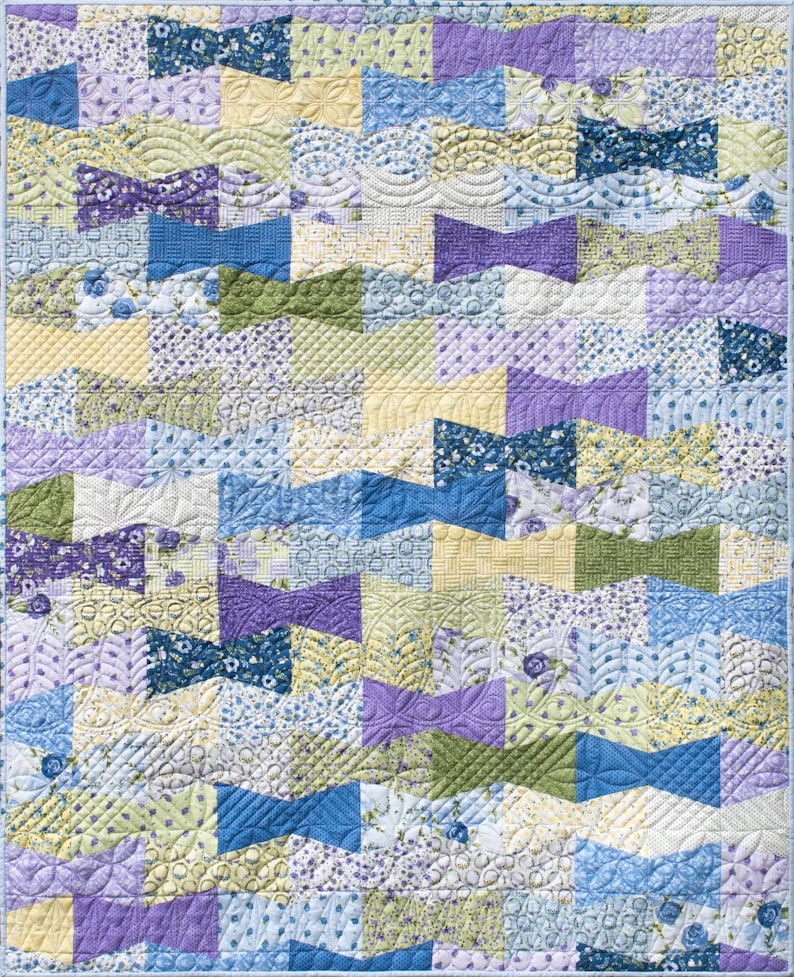 Op de afbeelding: Een patchwork quilt met een herhalend vlinderdaspatroon. De quilt heeft een verscheidenheid aan pastelkleuren, waaronder blauw, paars, geel en groen. De vlinderdasvormen zijn gewatteerd met ingewikkelde ontwerpen.