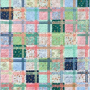 May include: A patchwork quilt with a grid design. The quilt is composed of squares in diverse colours and patterns, including floral prints, solid colours, and quilted designs. The colour scheme includes pink, blue, green, and orange, with a light blue border.