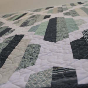 K&ouml;nnte beinhalten: Eine Steppdecke mit einem geometrischen Muster in Blaut&ouml;nen, Gr&uuml;nt&ouml;nen und Wei&szlig;. Die Steppdecke besteht aus verschiedenen Stoffen mit unterschiedlichen Texturen und Mustern.
