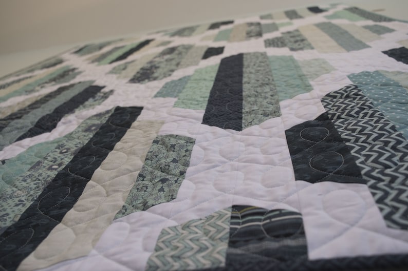 K&ouml;nnte beinhalten: Eine Steppdecke mit einem geometrischen Muster in Blaut&ouml;nen, Gr&uuml;nt&ouml;nen und Wei&szlig;. Die Steppdecke besteht aus verschiedenen Stoffen mit unterschiedlichen Texturen und Mustern.
