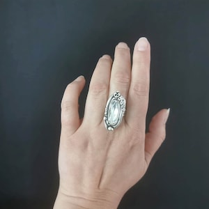 A silver plated ring with an oval-shaped clear crystal set in a decorative silver setting.