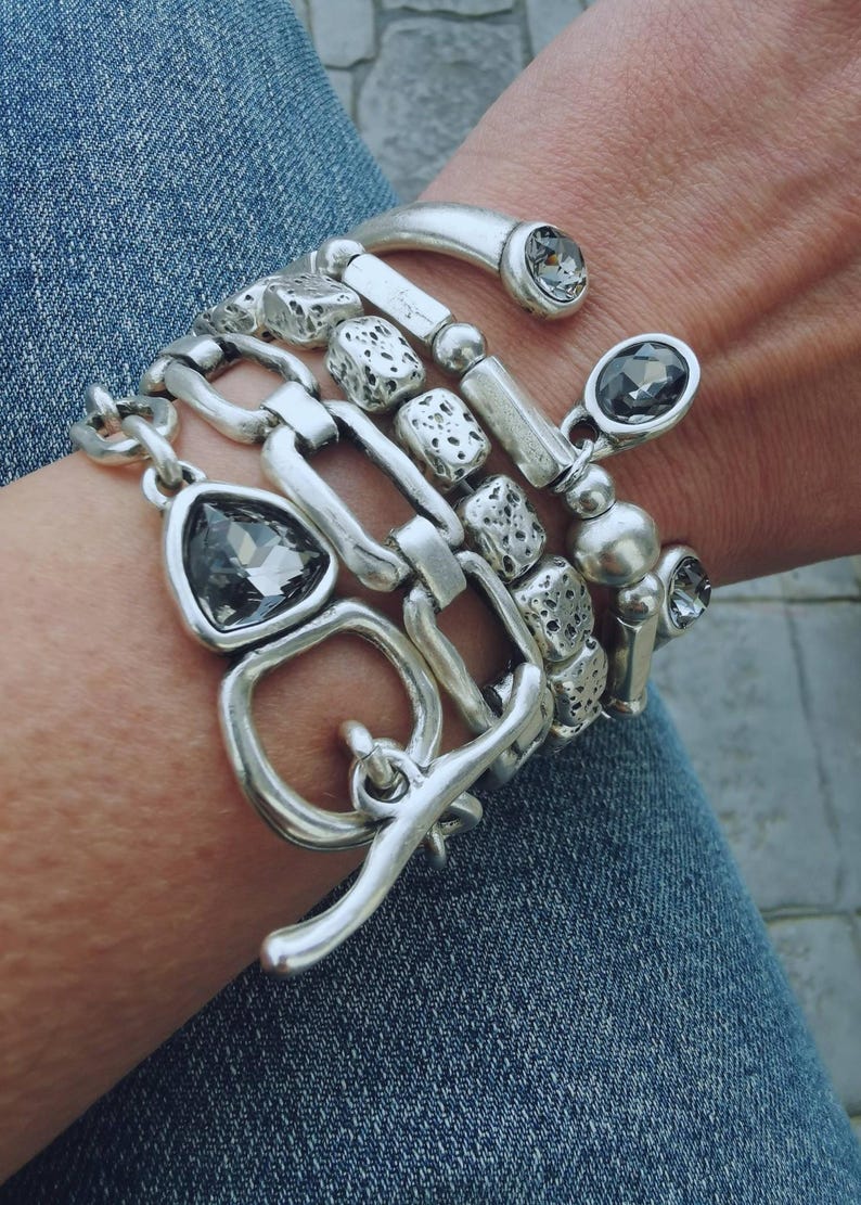 Set of 5 stacking silver plated bracelets on a woman wrist.