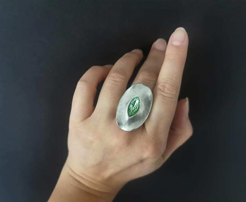 Puede incluir: Un anillo de plata con una piedra preciosa verde engastada en forma ovalada.